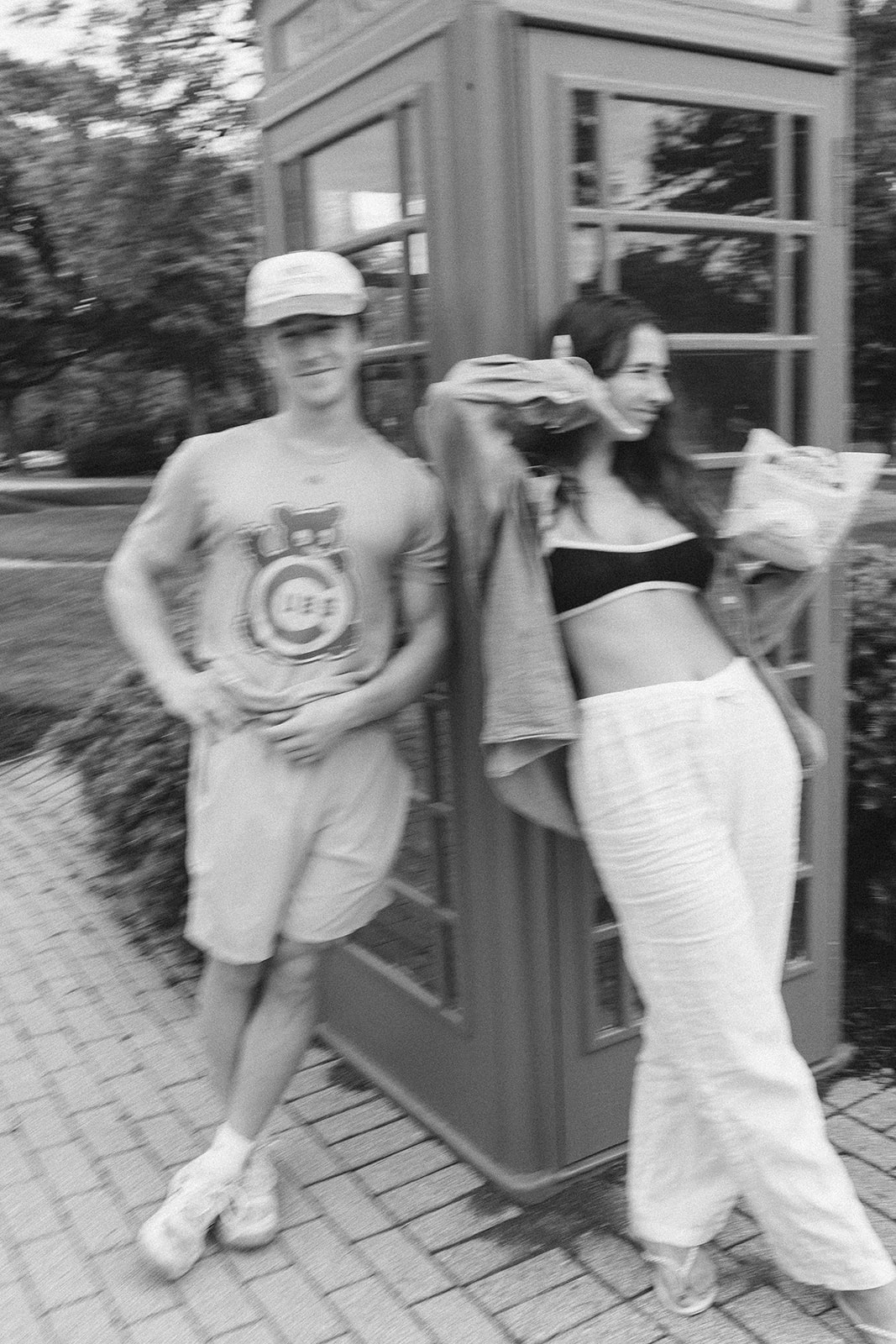 Cam and Kiersten leaning against a phone booth, black and white