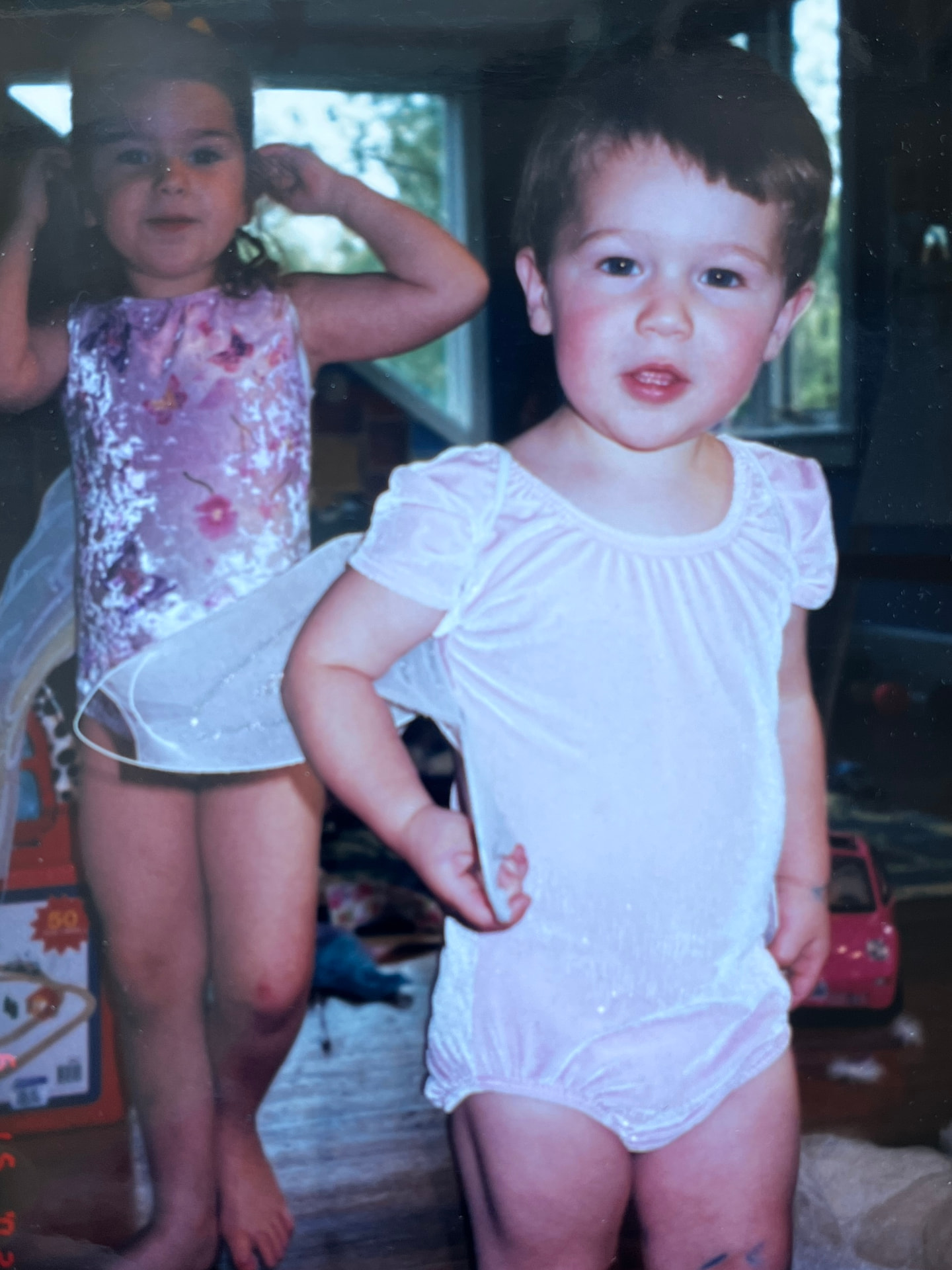 Cam as a toddler dressed up by his sisters in a pink leotard
